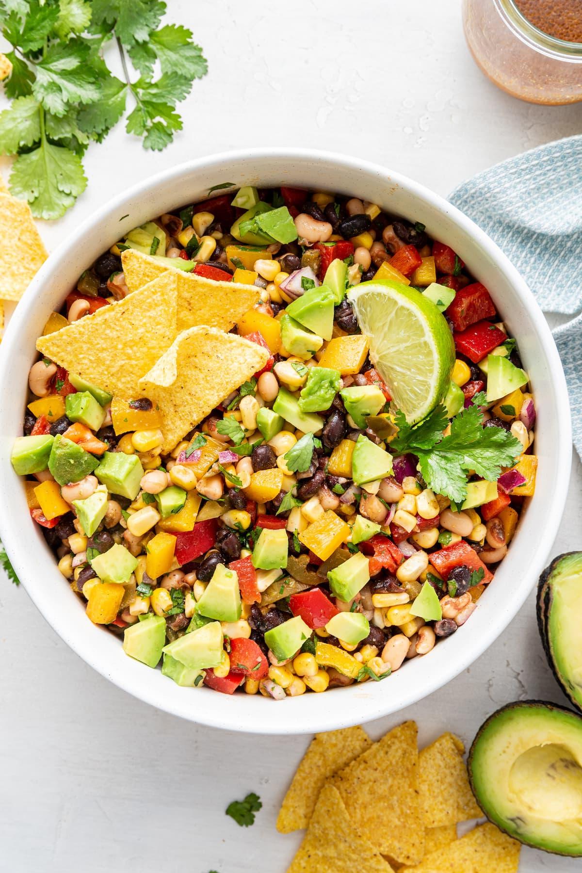 Καουμπόι Χαβιάρι 2 Ένα μπολ με σαλάτα Cowboy Caviar με κομμένο αβοκάντο, μια φέτα λάιμ και τσιπς τορτίγιας.
