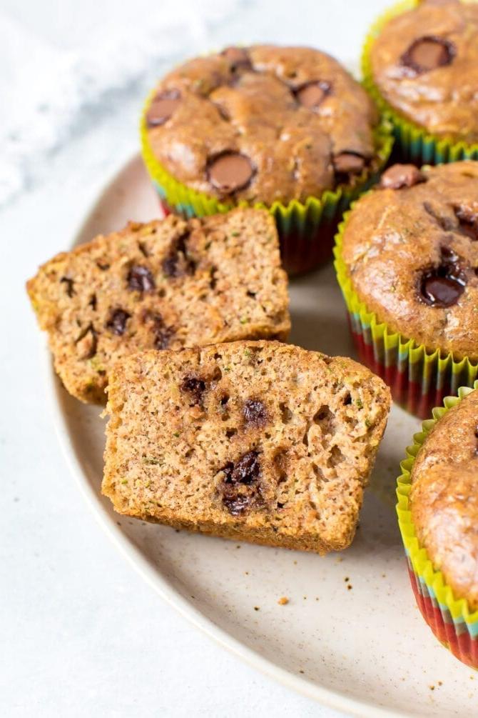 Μάφινς κολοκυθιού χωρίς αλεύρι 2 Πλάκα με muffins σε κοντινό πλάνο. Ένα muffin είναι κομμένο στη μέση και φαίνονται οι σταγόνες σοκολάτας.
