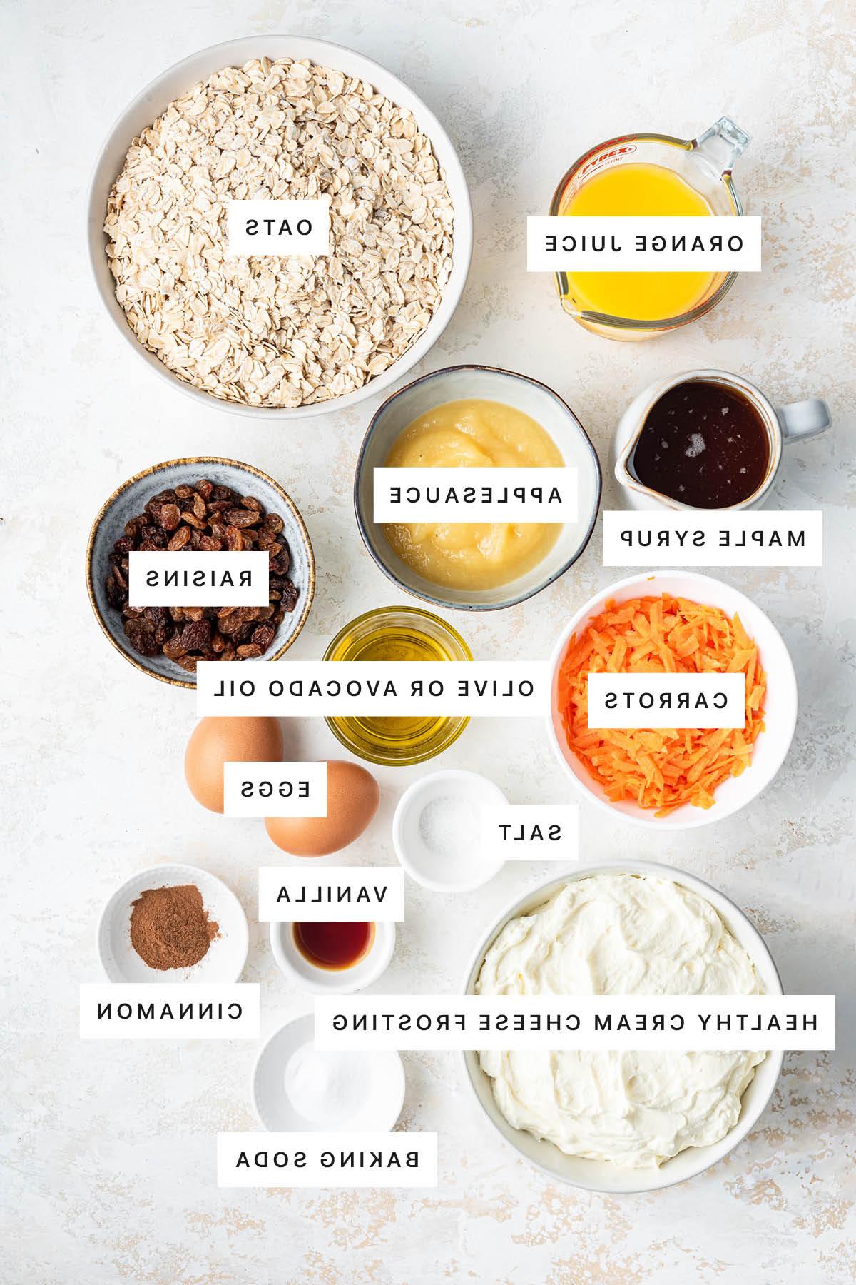 Κέικ βρώμης και καρότου 3 Ingredients measured out to make Oatmeal Carrot Cake: orange juice, oats, maple syrup, applesauce, raisins, carrots, olive oil, salt, eggs, vanilla, cinnamon, healthy cream cheese frosting and baking soda.