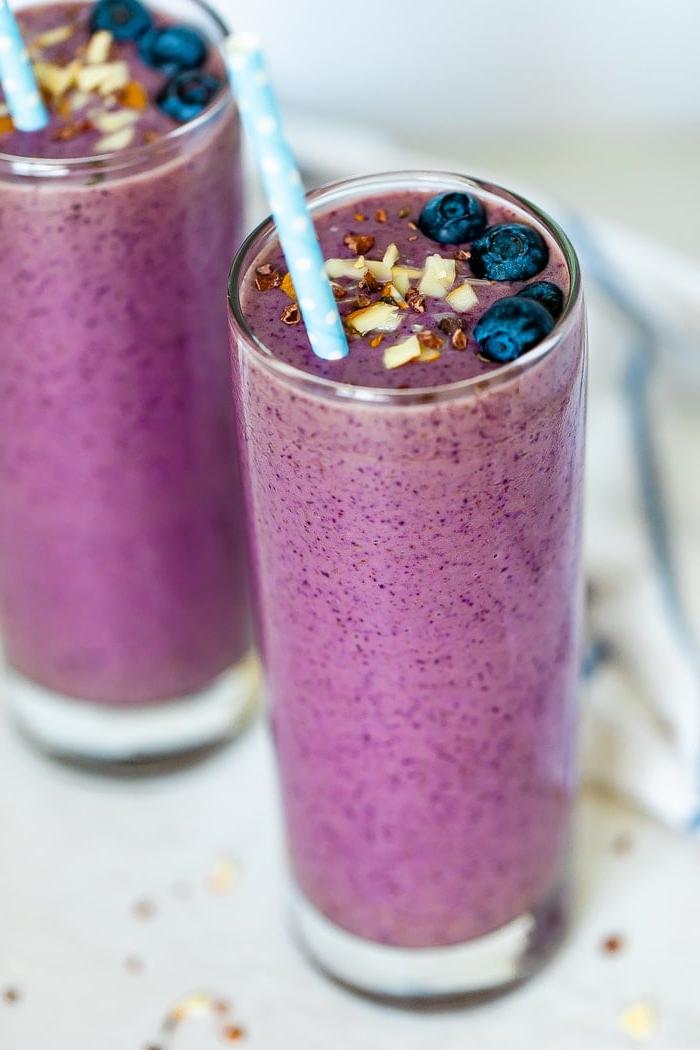 Σμούθι Υγιεινολάτρη (Εμπνευσμένο από Tropical Smoothie) 3 Δύο μωβ smoothie με επικάλυψη από ψιλοκομμένα αμύγδαλα, μύρτιλλα, κακαόψιχες και με δύο χάρτινα μπλε καλαμάκια με πουά.