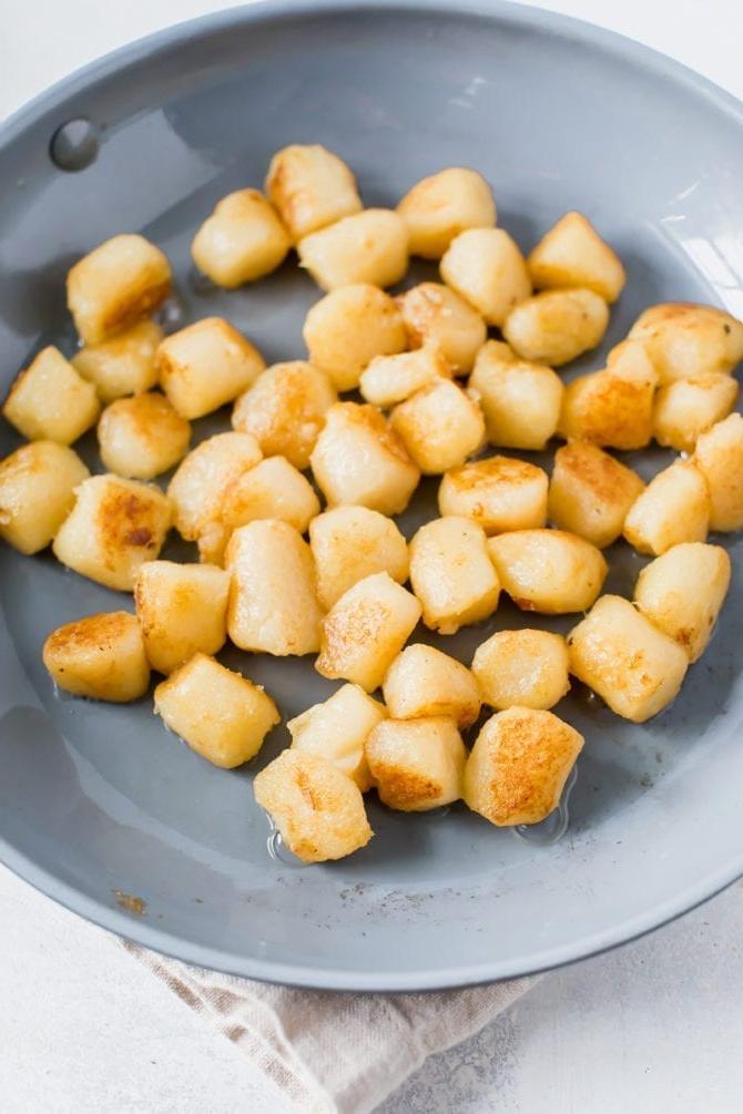 Trader Joe's cauliflower gnocchi sautéing in a skillet with olive oil.