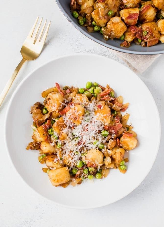 Plated cauliflower gnocchi sautéed with onions, peas and turkey bacon. Topped with parmesan cheese.