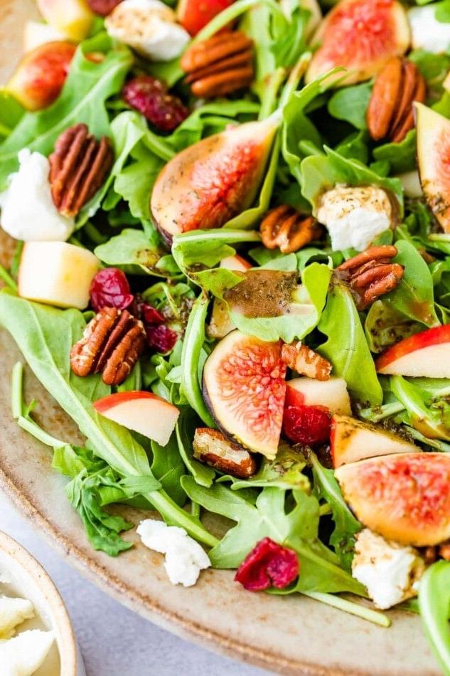 Σαλάτα Σύκων με Ρόκα και Κατσικίσιο Τυρί 5 Μια κοντινή φωτογραφία σύκων, πεκάν, κομματιών μήλου και αποξηραμένων κράνμπερι σε ένα στρώμα ρόκας.