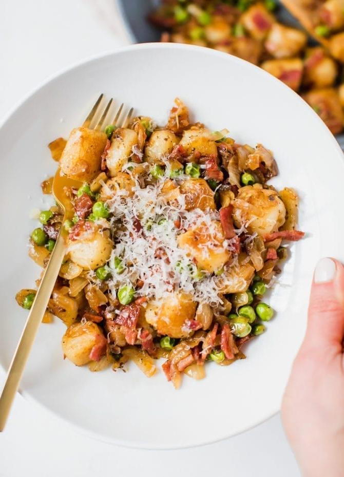 Plated cauliflower gnocchi sautéed with onions, peas and turkey bacon. Topped with parmesan cheese.