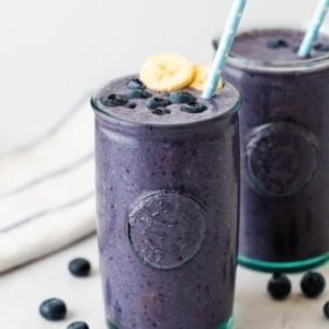 Μύρτιλο Σμούθι 6 Smoothie με μύρτιλα σε ποτήρι, διακοσμημένο με μύρτιλα, φέτες μπανάνας και καλαμάκι.