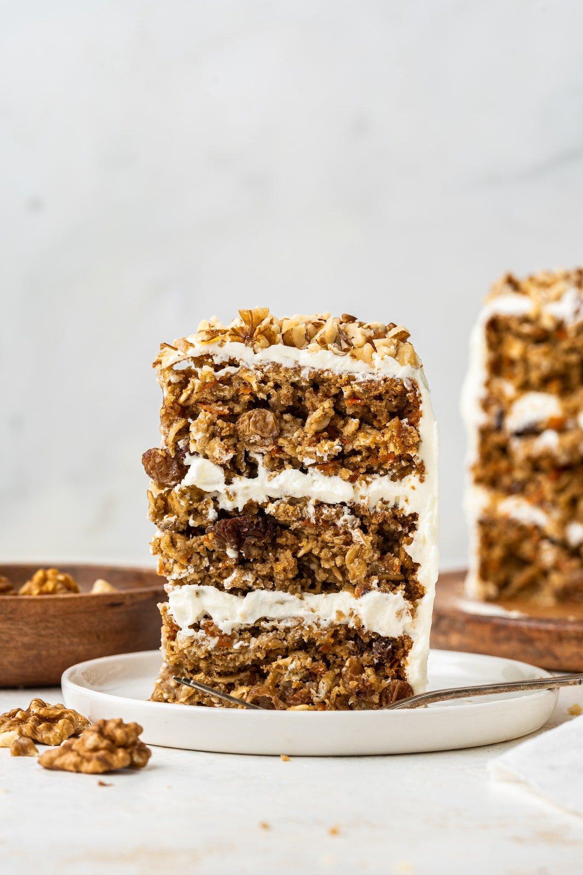 Κέικ βρώμης και καρότου 7 A slice of a 3-layer oatmeal carrot cake standing up vertical on a white plate.