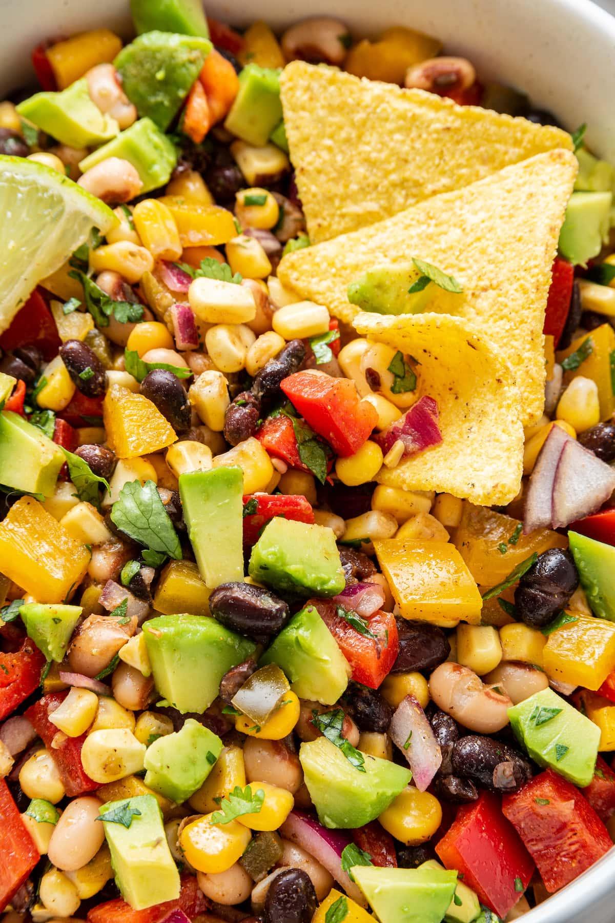 Καουμπόι Χαβιάρι 10 Ένα μπολ με σαλάτα Cowboy Caviar με κομμένο αβοκάντο, μια φέτα λάιμ και τσιπς τορτίγιας.