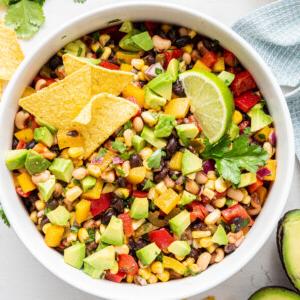Καουμπόι Χαβιάρι 12 Ένα μπολ με σαλάτα Cowboy Caviar με κομμένο αβοκάντο, μια φέτα λάιμ και τσιπς τορτίγιας.