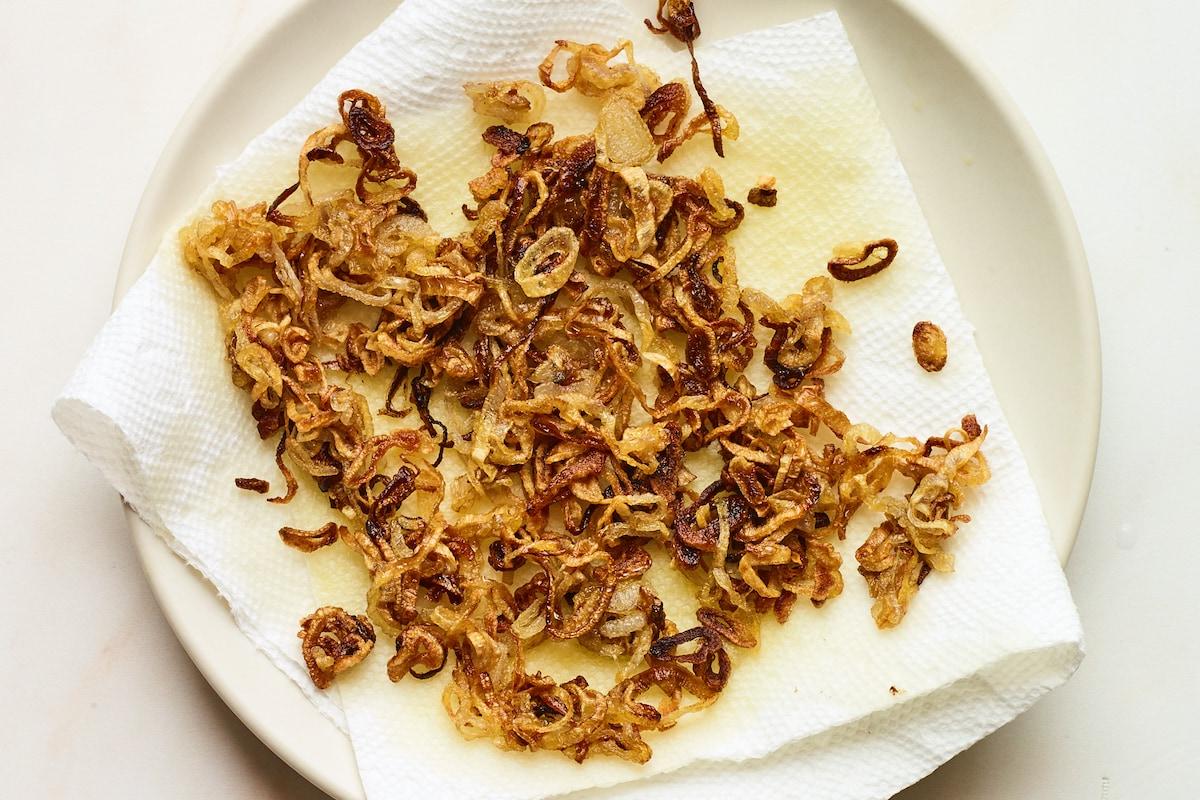 Φασολάκια Σαλάτα 9 Crispy fried shallots on a paper towel, releasing excess oil.