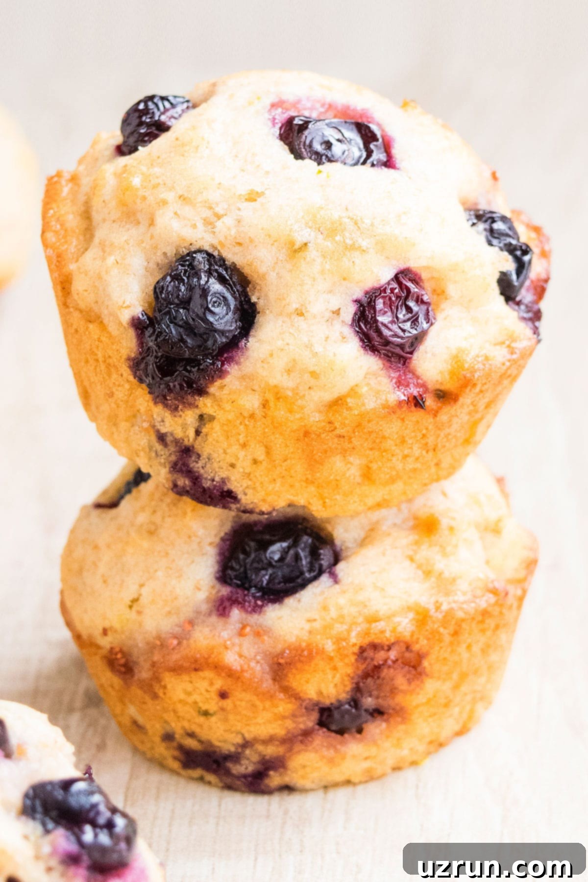 Stack of Soft Lemon Blueberry Muffins on Light Brown Background.