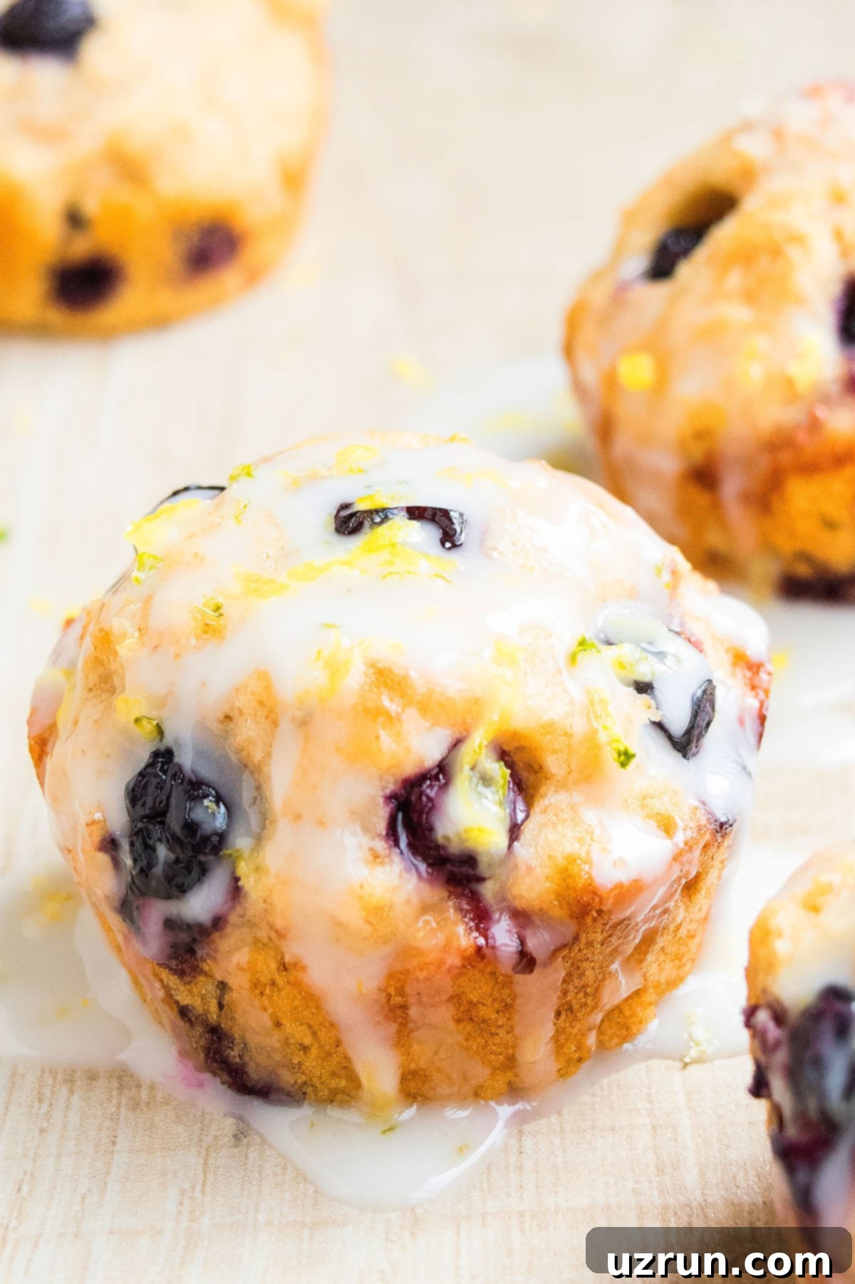 Glazed Lemon Blueberry Muffins 6 Glazed Berry Muffin on Light Brown Background.