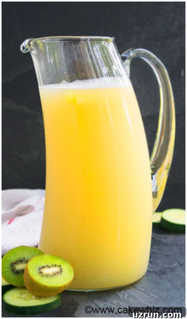 Sparkling Kiwi Lemonade, served in a tall glass with fresh kiwi and lemon slices, and a mint sprig