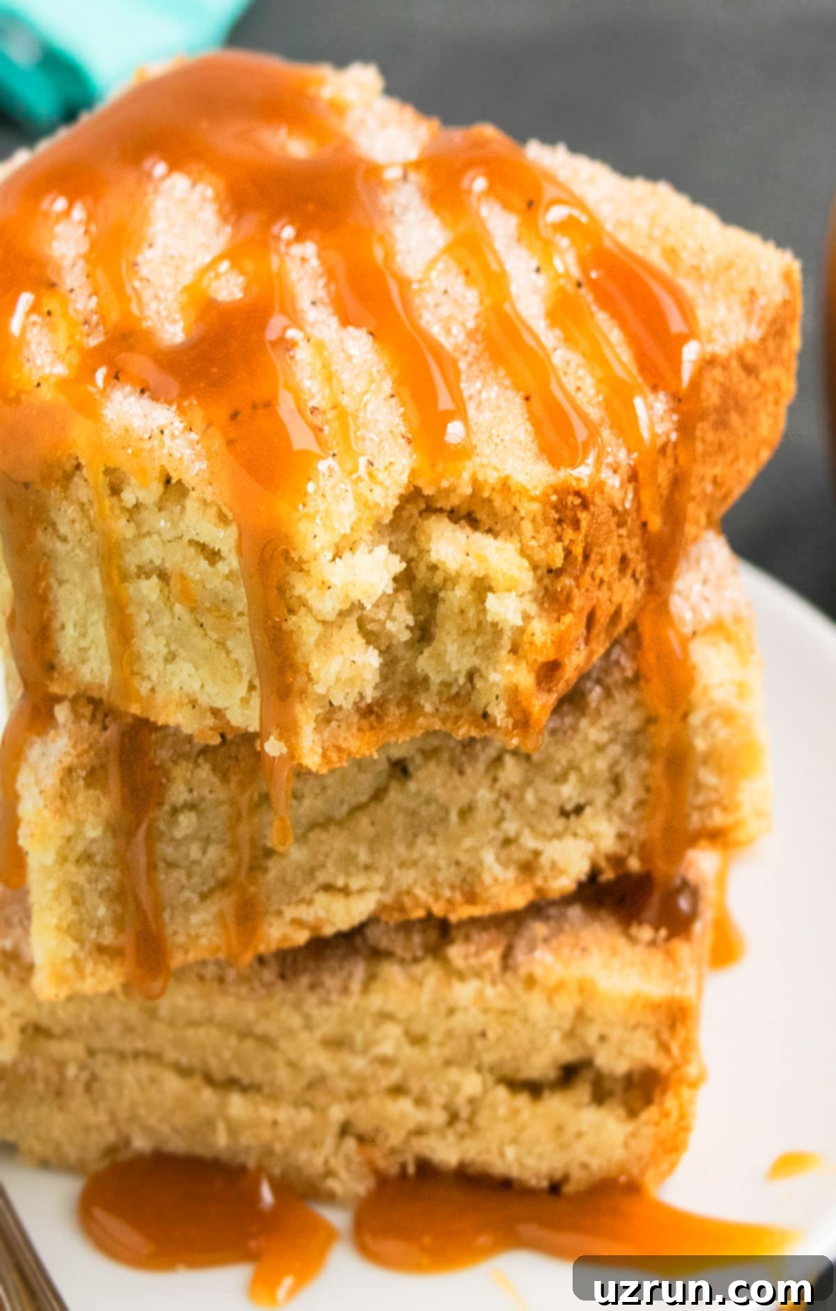 Perfectly Soft and Chewy Snickerdoodle Bars 12 Stack of Cinnamon Spice Blondie Bars on White Plate With Drizzle of Caramel Sauce.