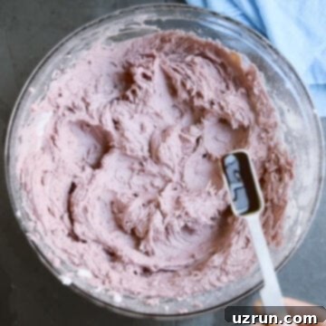 Effortless Blackberry Buttercream Frosting 7 Extract being added to mixture in glass bowl.