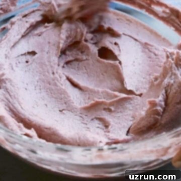 Effortless Blackberry Buttercream Frosting 8 Spatula used to smooth out icing in glass bowl.