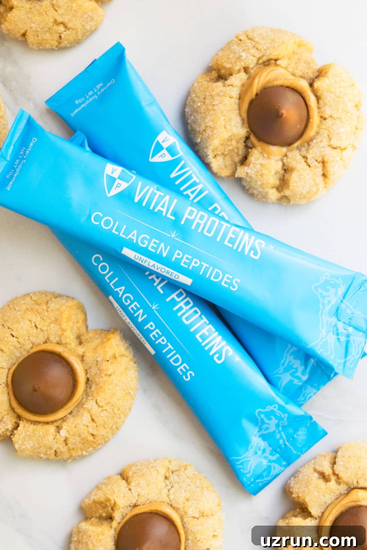 Easy Peanut Butter Blossoms with Hershey's Kisses 4 Vital Proteins Collagen Packets on White Marble Background.