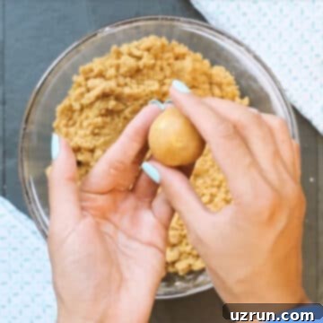 Easy Peanut Butter Blossoms with Hershey's Kisses 9 Cookie dough balls being formed with hands.