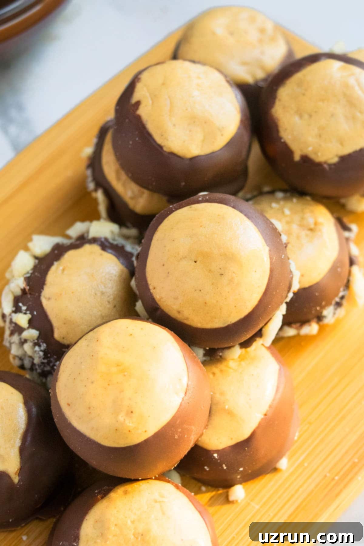 Quick & Easy Peanut Butter Buckeyes 3 Chocolate Peanut Butter Buckeye Balls on Wooden Tray.