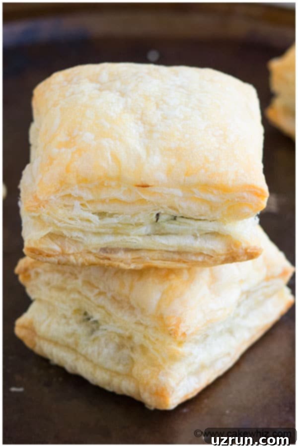 Irresistible Spinach and Feta Bites 3 Stack of Vegetarian Spinach Puffs on Dark Metal Tray.