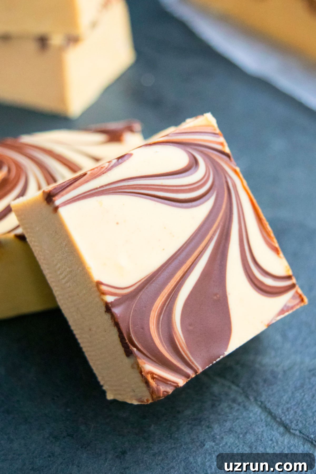 Chocolate Peanut Butter Swirl Fudge 10 Closeup Shot of Slice of Chocolate Swirled Fudge on Gray Background.