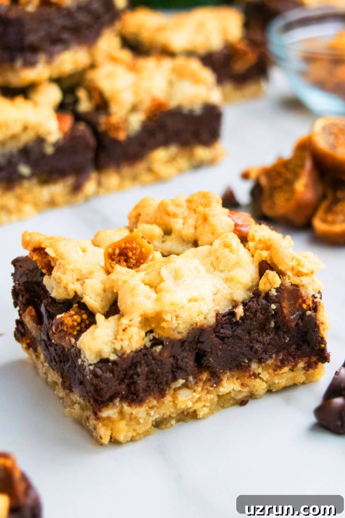Chocolate Oatmeal Crumb Bars 4 Single slice of a homemade chocolate crumb bar with a visible oatmeal base and fudgy chocolate layer, set on a white marble background.