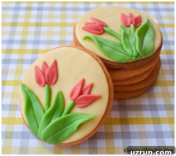 Easy Tulip Cookies Decorated With Fondant on a Gingham Yellow and Gray Background, showcasing vibrant yellow, pink, and green tulip designs.