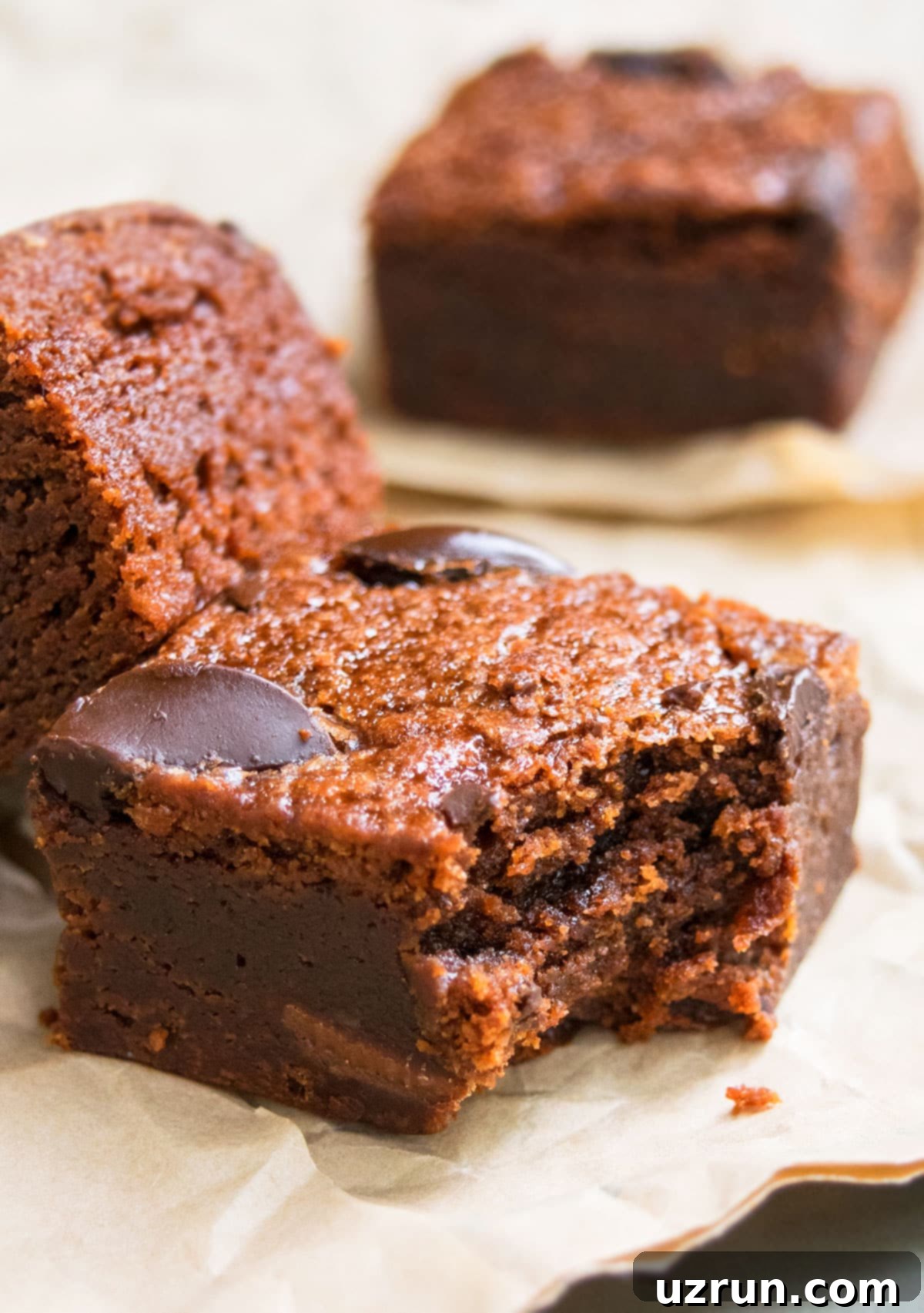 Delightfully Simple Gluten Free Black Bean Brownies 3 Partially Eaten Slice of Fudgy Brownie on Brown Parchment Paper.