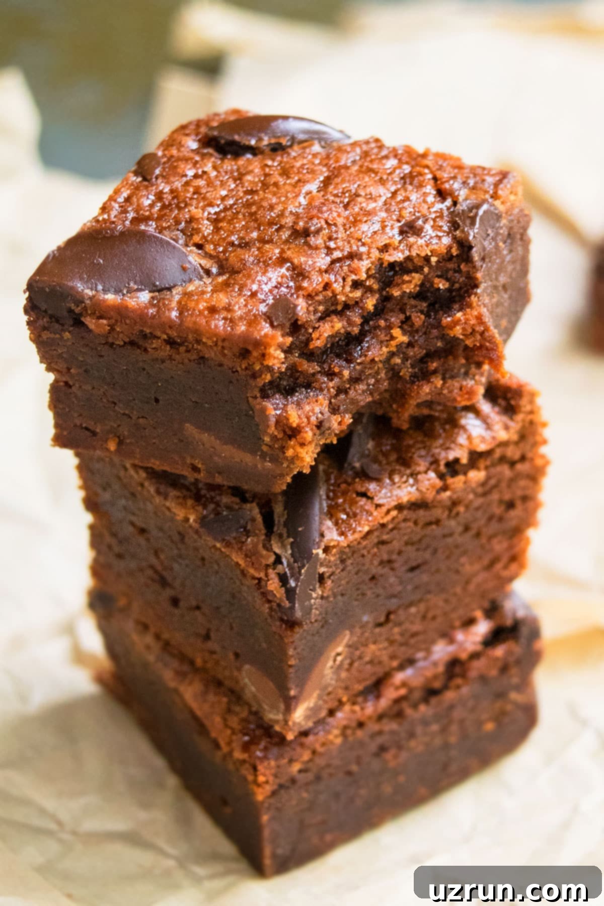 Delightfully Simple Gluten Free Black Bean Brownies 10 Stack of Three Homemade Brownie Slices With One on Top That's Partially Eaten on Brown Parchment Paper.