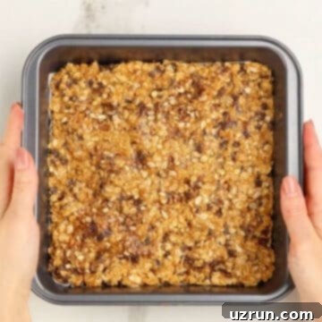Effortless No Bake Granola Bars 8 Mixture spread evenly in a lined pan.