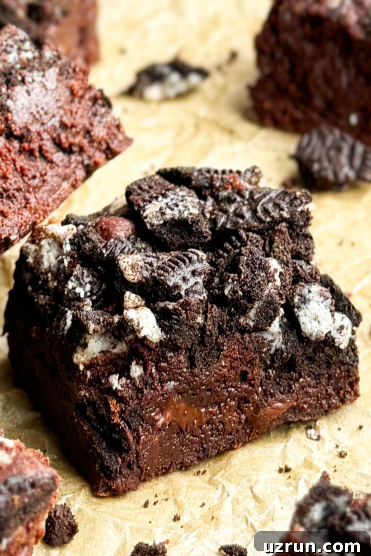 Easy Fudgy Oreo Brownies 11 Close-up shot of a perfect slice of Fudgy Chocolate Brownie on brown parchment paper, showing its dense interior and Oreo topping.