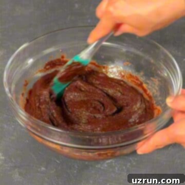 Easy Fudgy Oreo Brownies 6 Batter in glass bowl being mixed with a spatula until smooth.