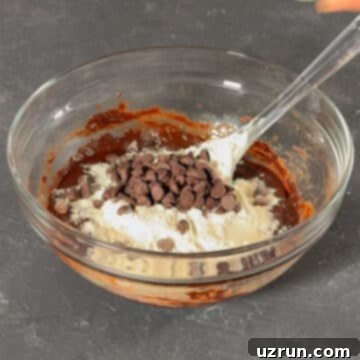 Easy Fudgy Oreo Brownies 7 Glass bowl with chocolate mixture, flour, and chocolate chips added.