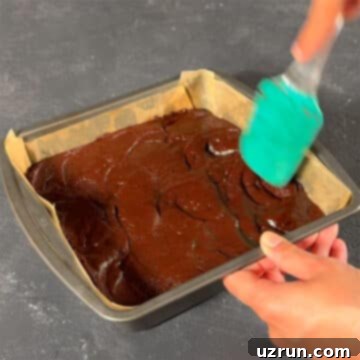 Easy Fudgy Oreo Brownies 9 Brownie batter being spread evenly in a parchment-lined square pan.