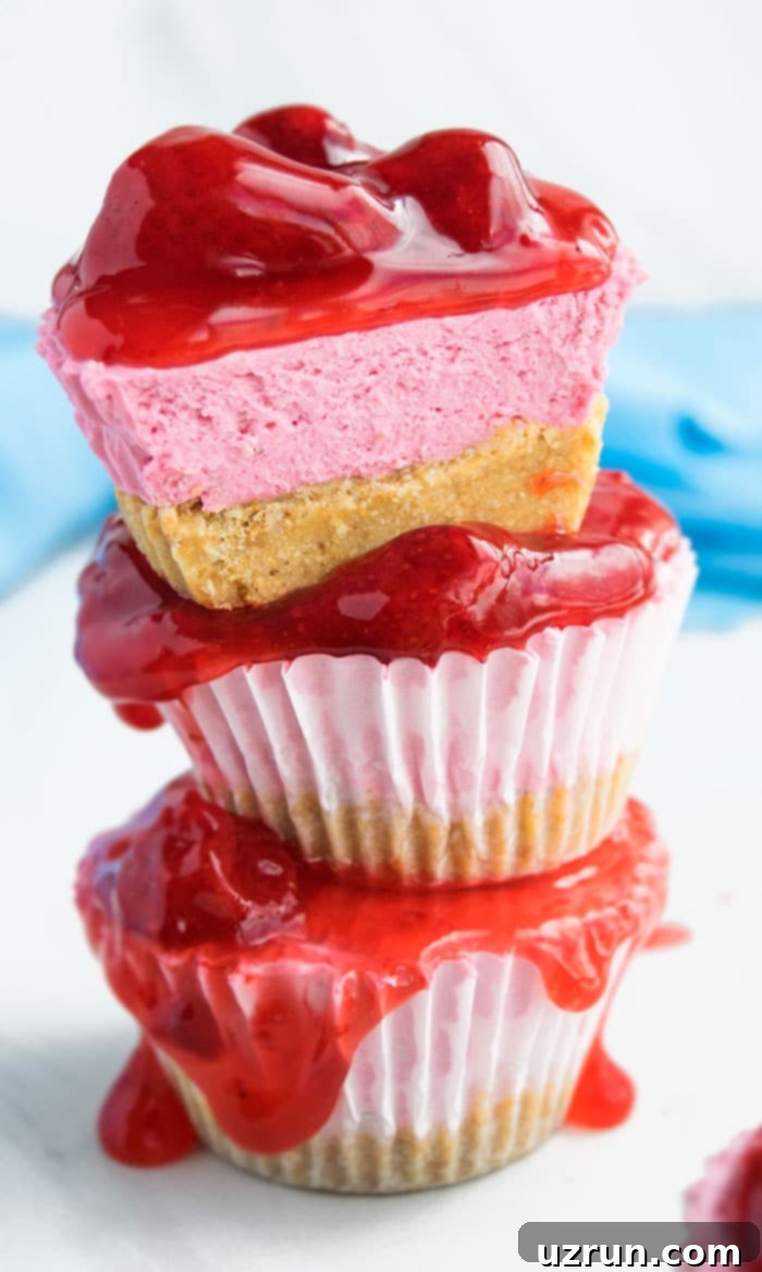 Mini Strawberry Cheesecake Cupcakes 4 Easy No Bake Cheesecakes Stacked on White Dish With One Sliced in Half.