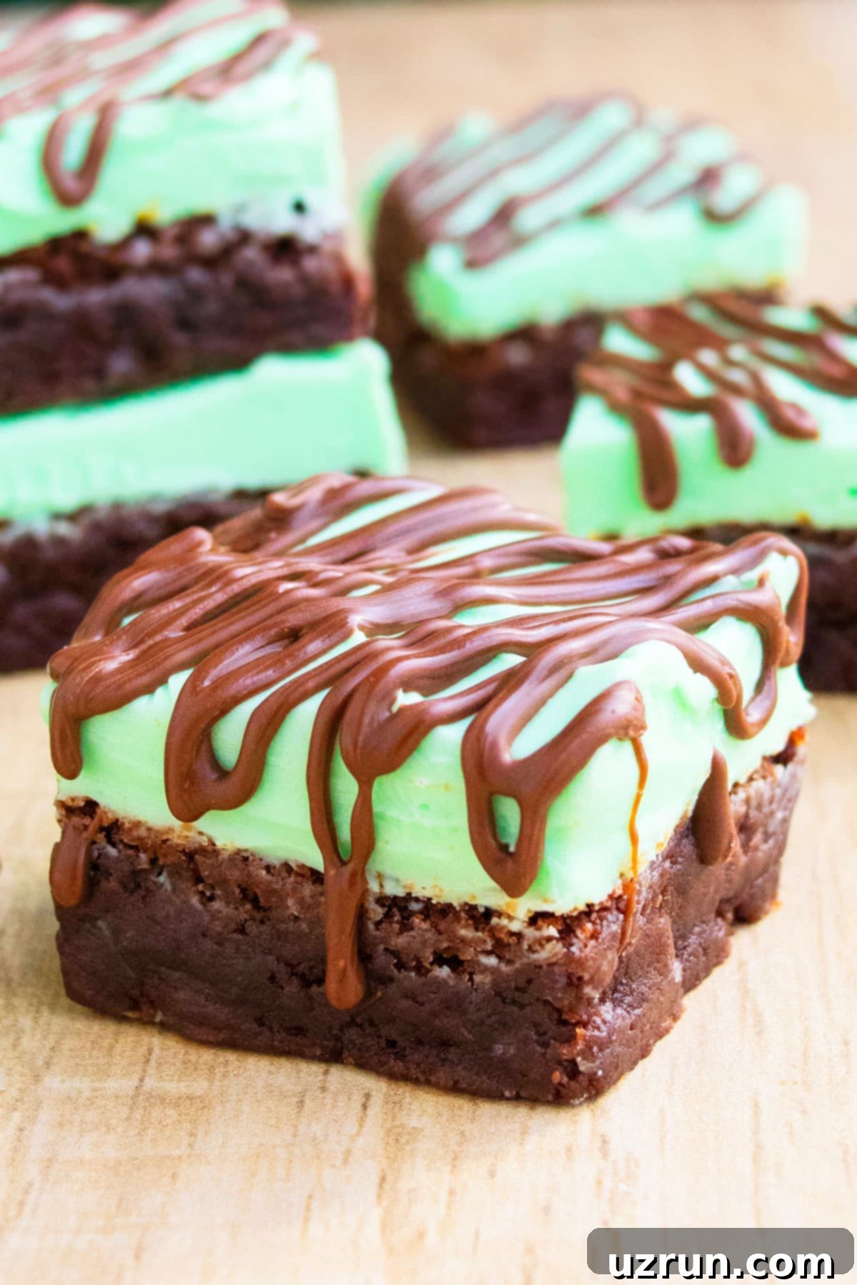 Fudgy Chocolate Mint Brownies 3 Slice of Brownie With Frosting and Chocolate Drizzle on Wood Background.