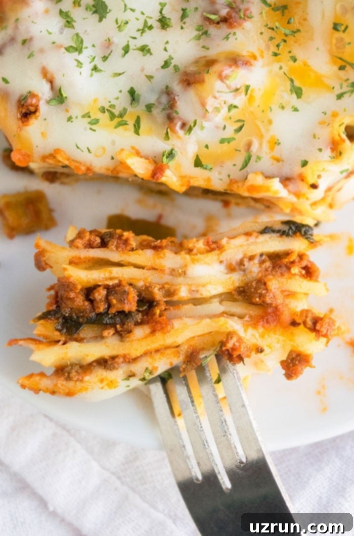 Fork Full of Lasagna on White Dish.