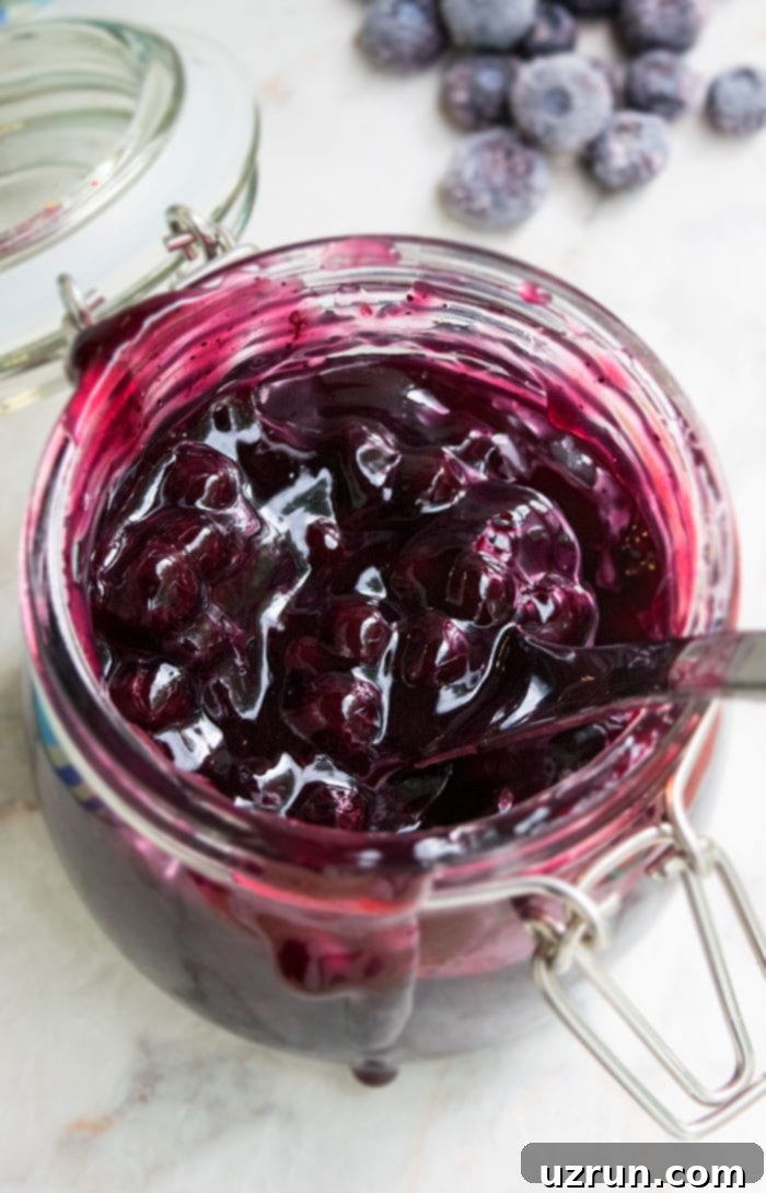 Easy Blueberry Pie Filling in Glass Jar on White Marble Background. 