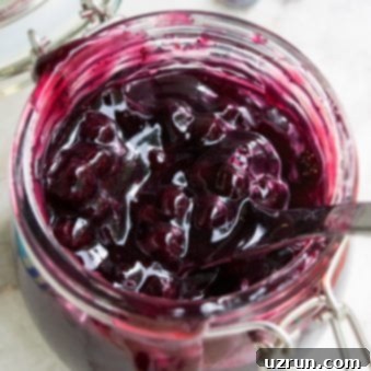 Easy Blueberry Pie Filling in Glass Jar on White Marble Background.