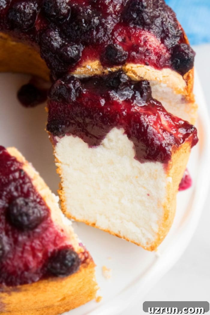 Fluffy Homemade Angel Food Cake 3 Slice of Angel Food Cake From Scratch With Blueberry Topping on White Cake Stand. A delightful and fresh dessert.