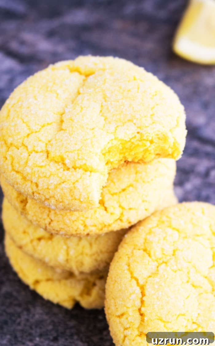Effortless Homemade Lemon Cookies 4 Stack of Yellow Summer Cookies on Rustic Gray Background With One Partially Eaten.
