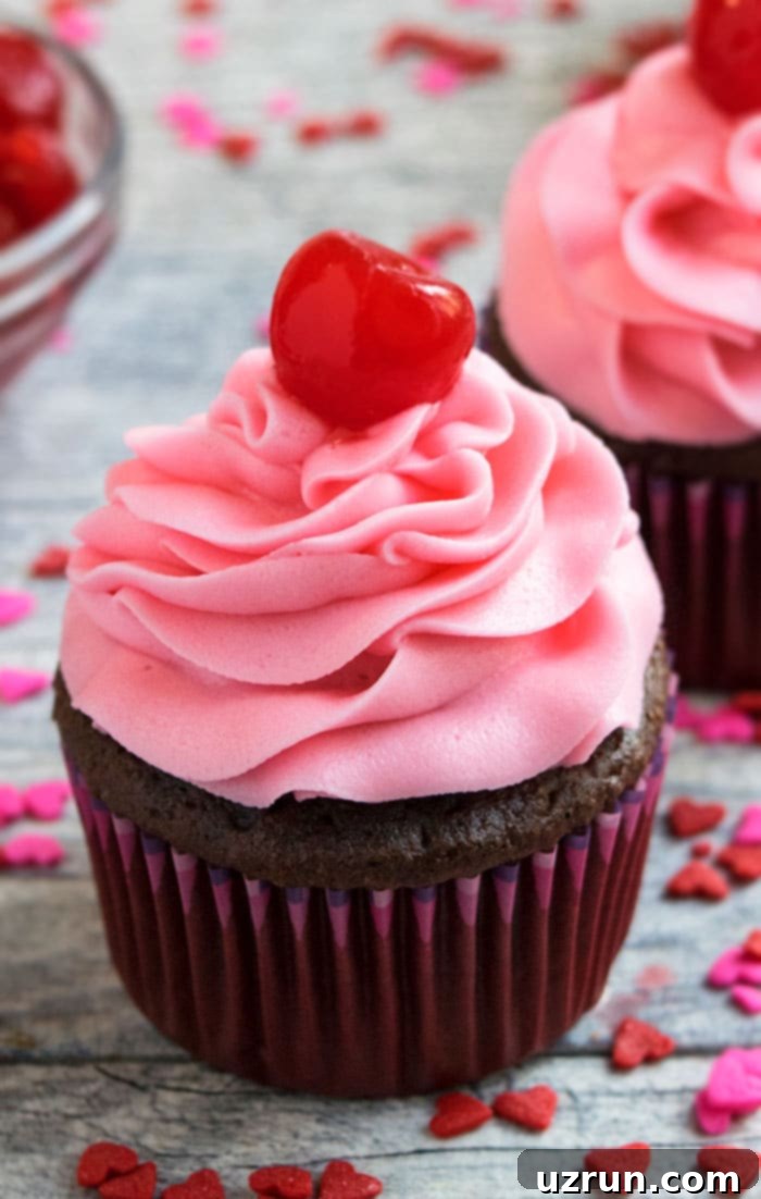 Easy Maraschino Cherry Frosting (Buttercream Icing) Piped on Top of Chocolate Cupcake on Rustic Gray Background. 