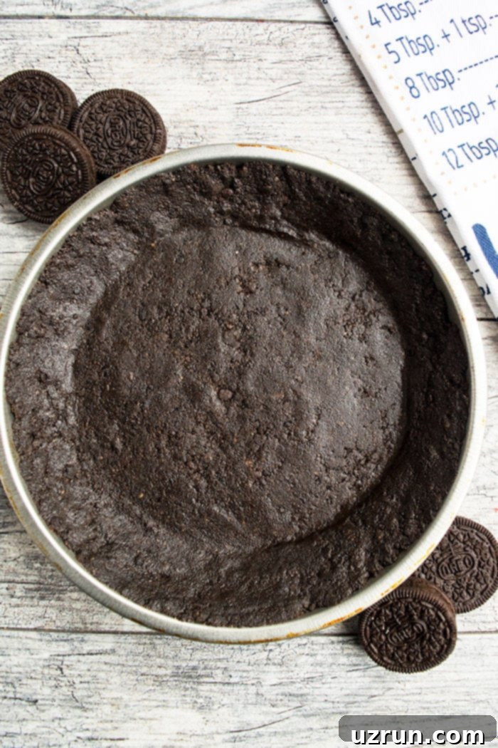 Easy No Bake Oreo Pie Crust on Rustic Gray Background- Overhead Shot. A dark, perfectly pressed Oreo crust sits ready for filling.