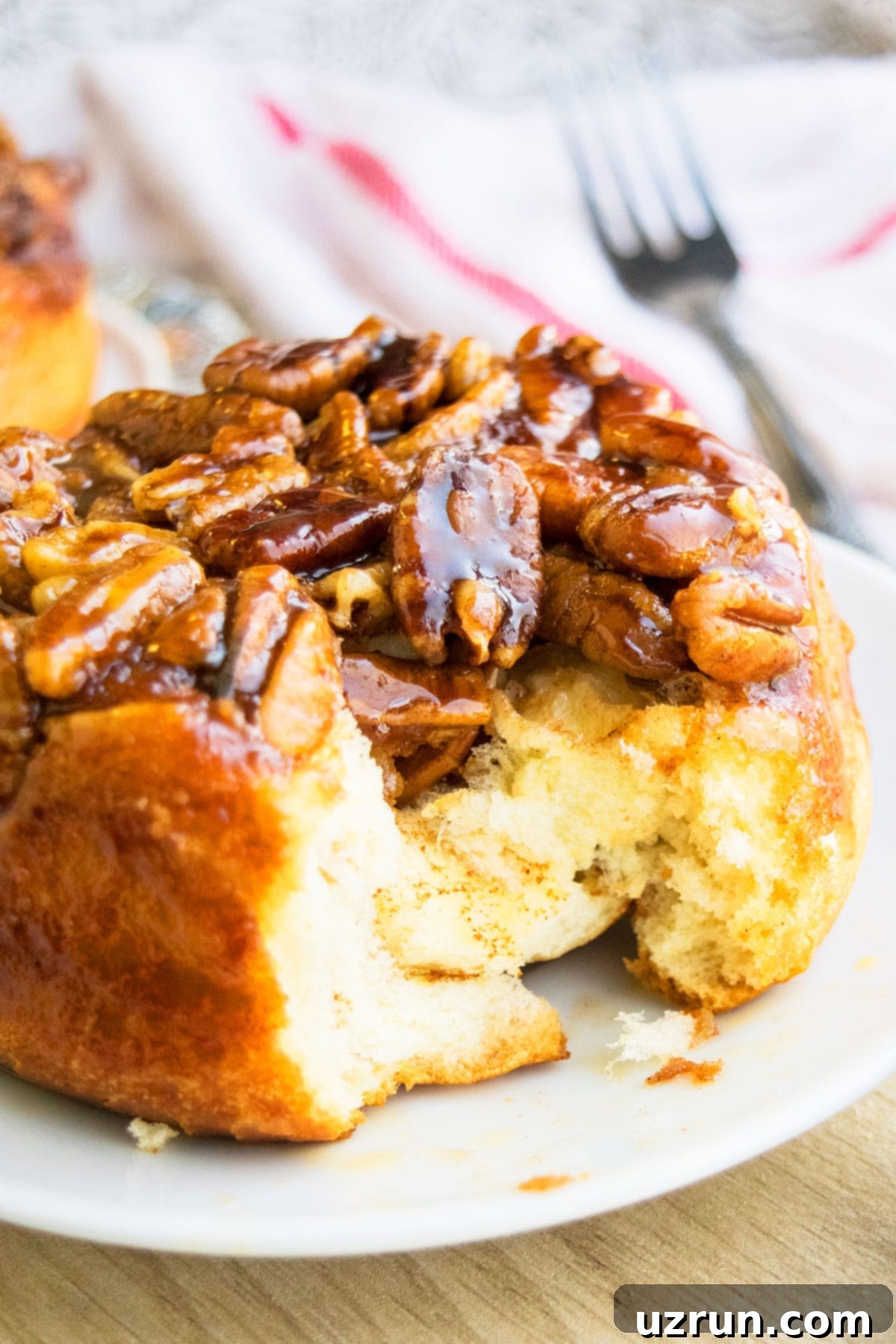 Pecan Caramel Sticky Buns 3 Partially Eaten Sweet Caramel Pecan Rolls on White Dish.