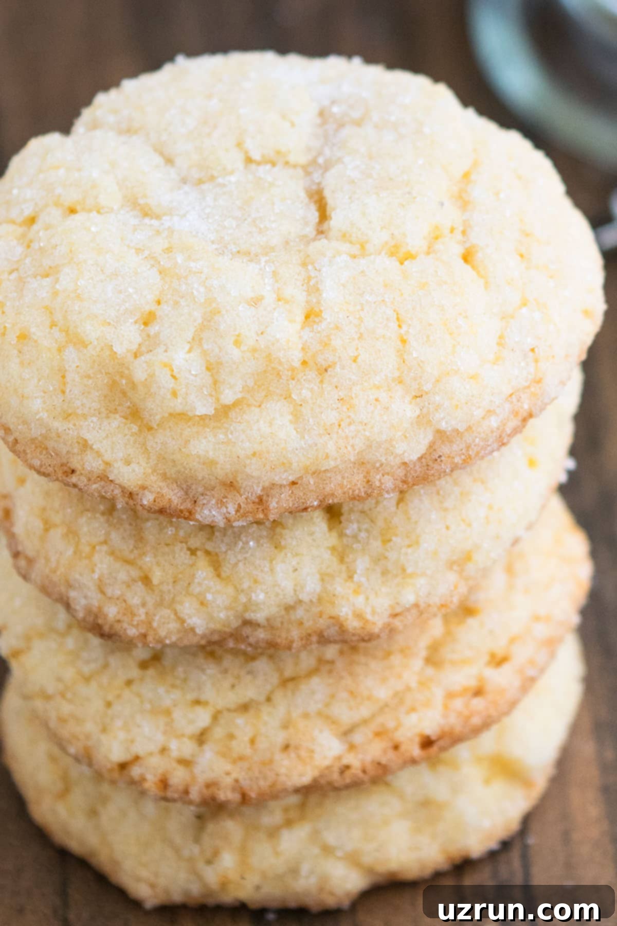 Stack of Soft and Chewy Christmas Cookies on Wood Background. Several freshly baked eggnog cookies stacked neatly, showcasing their golden color and inviting texture, with a cake mix box in the background.
