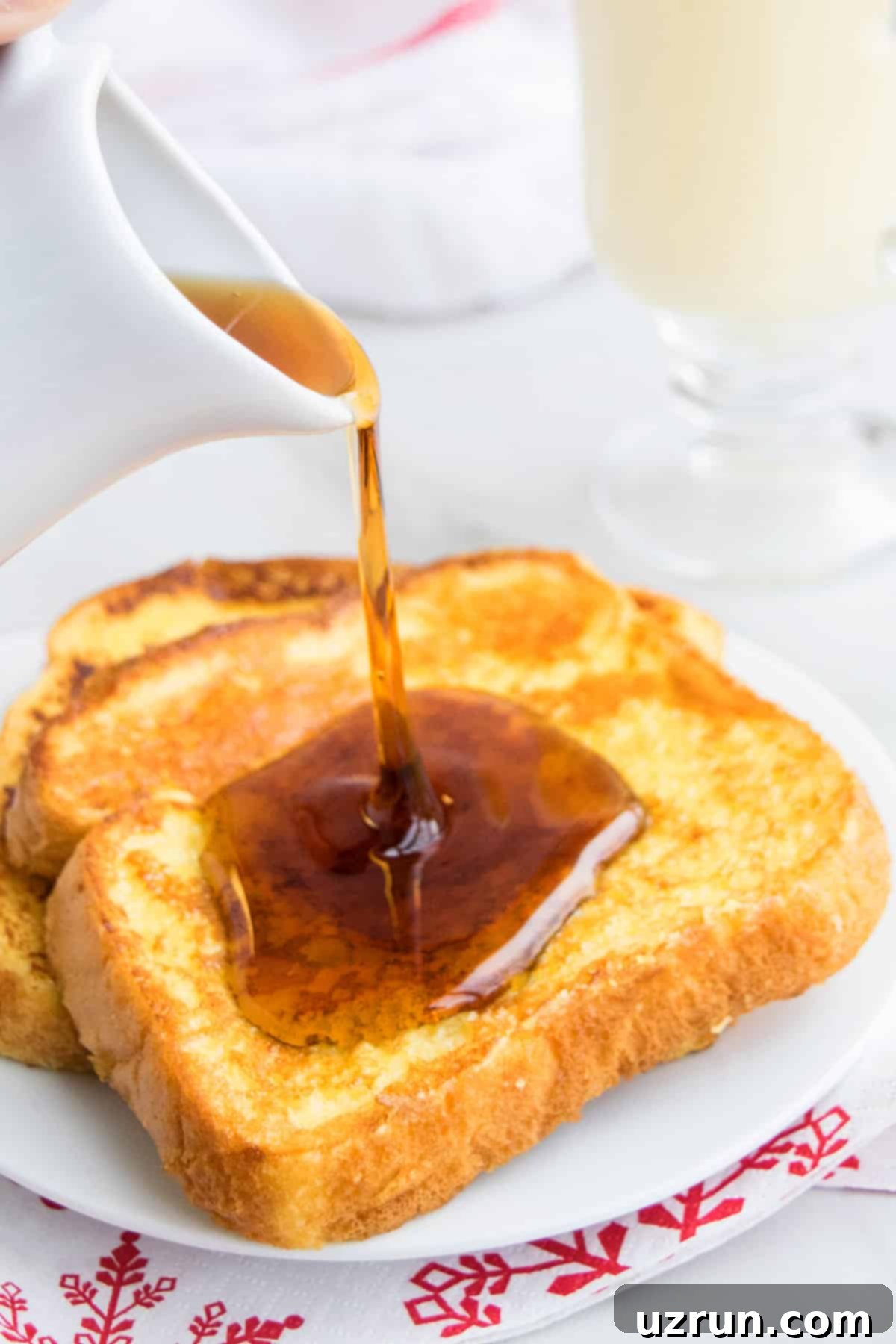 Perfect Easy Eggnog French Toast 3 Syrup Being Drizzled on Top of French Toast in White Dish.