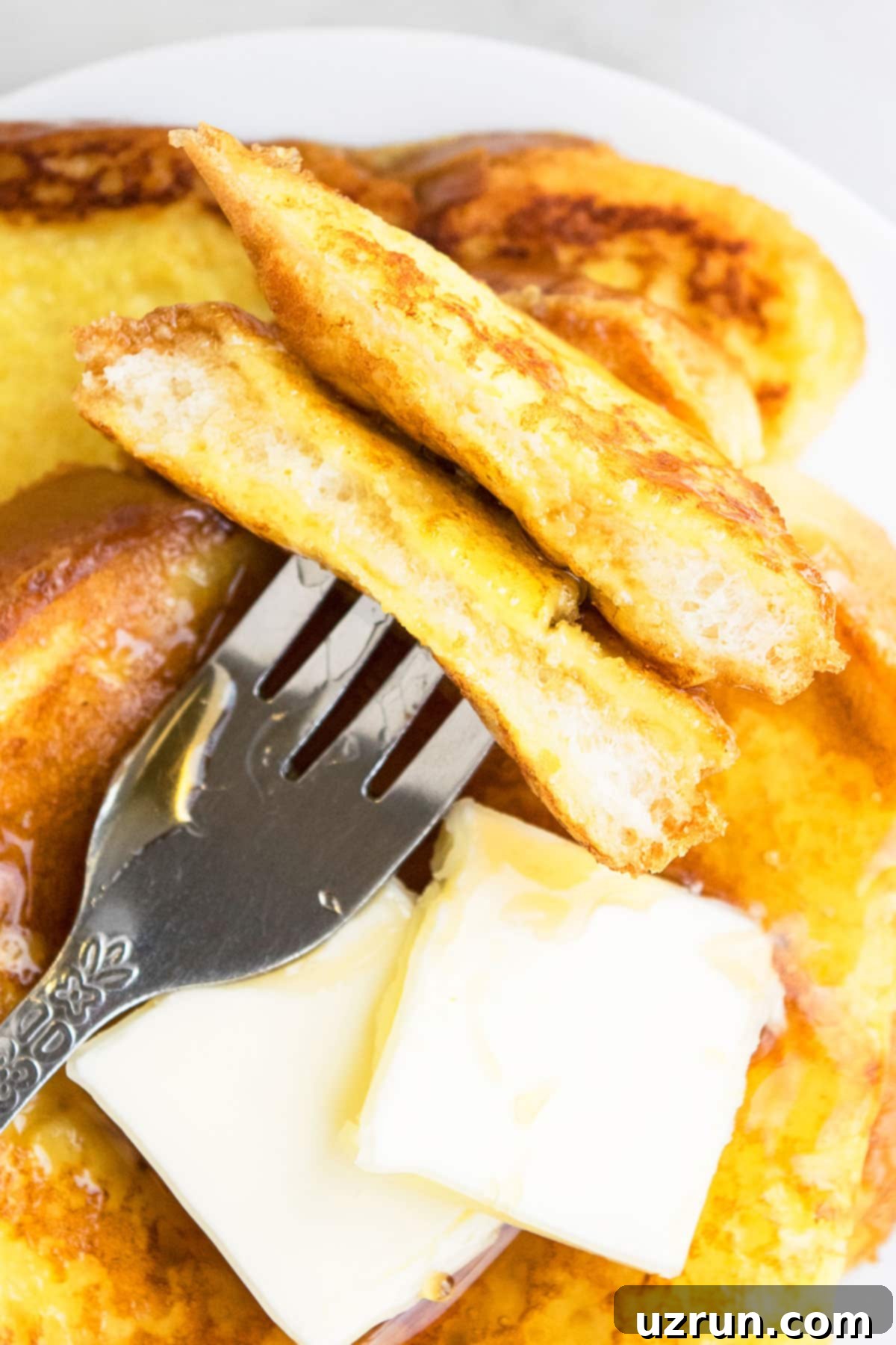 Perfect Easy Eggnog French Toast 4 Closeup Shot of Fork Full of Christmas French Toast Breakfast on White Dish.