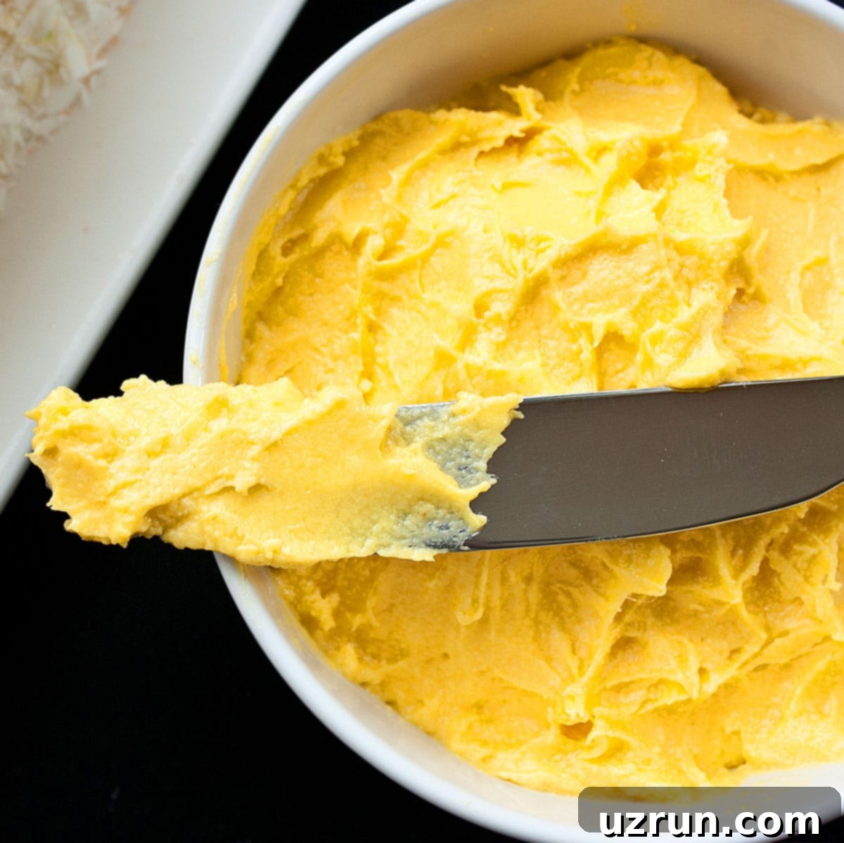 Easy Mango Frosting in White Bowl With Spatula. 