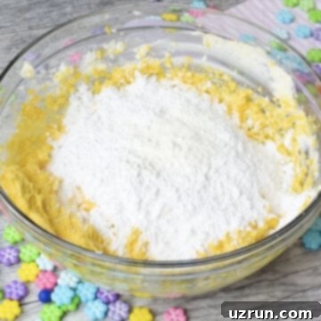 Easy Mango Buttercream Frosting 8 Powdered sugar added to mango mixture in glass bowl.