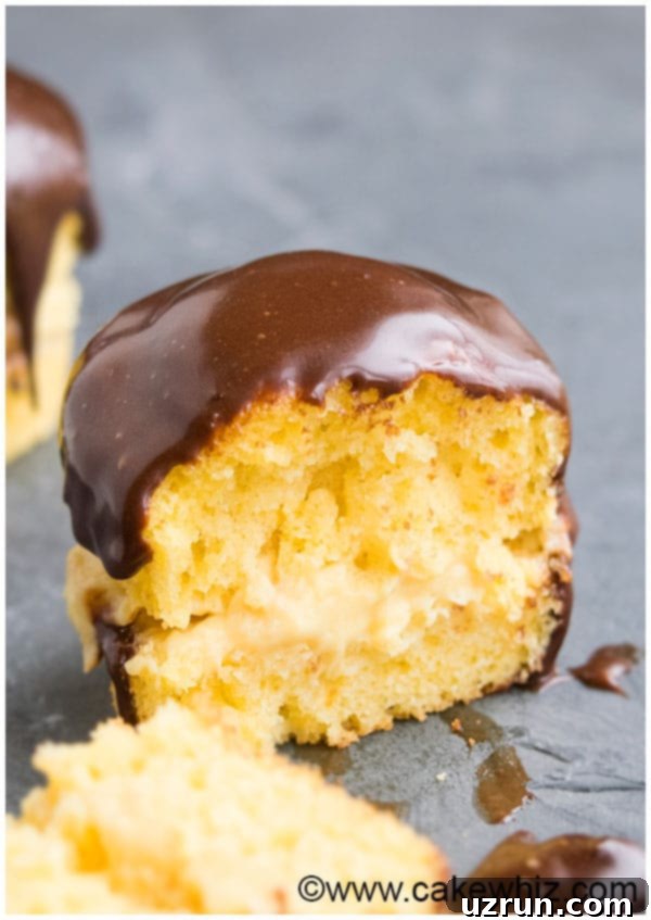 Boston Cream Dream Cupcakes 3 Closeup shot of a sliced vanilla cupcake revealing vanilla pudding filling and chocolate ganache topping