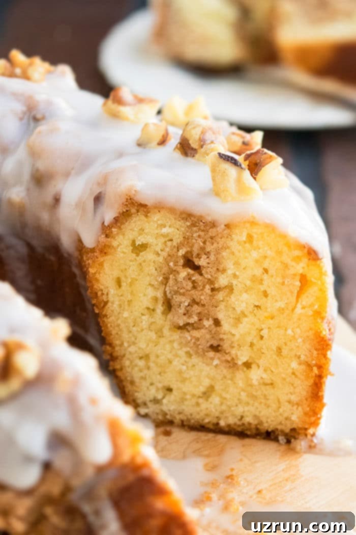 Easy Sock It To Me Cake with Cake Mix 4 Sliced Bundt Cake With Cinnamon Pecan Streusel Filling and Vanilla Glaze on Rustic Wood Board- Closeup Shot